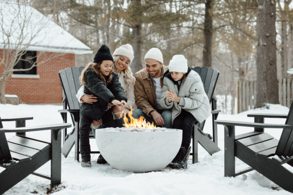 Family gathered around a fire pit in the snow
